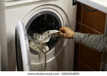 Person Loading Laundry into Front-Loading Washing Machine at Home