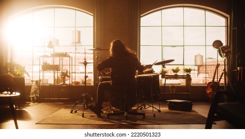 Person With Long Hair Sitting With Their Back To Camera, Playing Drums During A Band Rehearsal In A Loft Living Room With Warm Sunlight. Drummer Practising Alone Before A Concert On Stage.