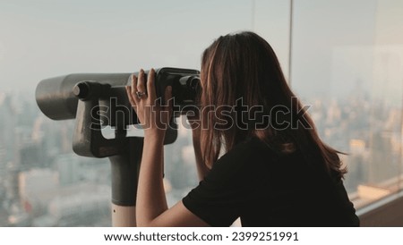 Person looking in binoculars telescope on observation deck for tourist. Tower sky viewpoint top floor. City skyline panorama at day time. Travel, tourism, outdoor lifestyle holiday vacation. Back view