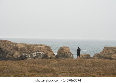 Person Looking Over Ocean At Cliff