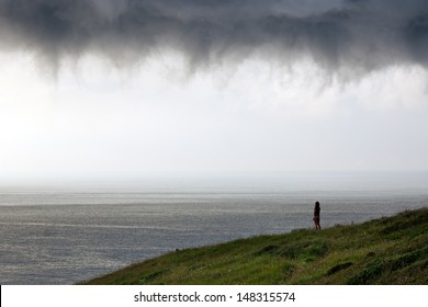 person looking at sea with stormy clouds