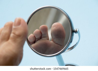 Person looking at the sole of the foot in a mirror, to check if there is no diabetic foot, as possible sores
