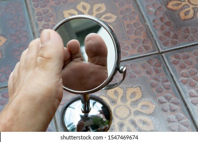 Person looking at the sole of the foot in a mirror, to check if there is no diabetic foot, as possible sores