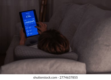 Person lying in bed and using a digital tablet to view sleep tracking results, showing a short duration of sleep and indicators of insufficient rest and exhaustion