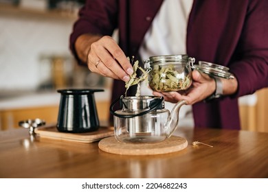 A Person Making Tea, Using A Dried Herb, Putting In A Teapot.