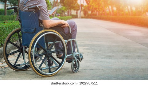 A Person Man with Disability on Wheelchair using Smartphone while Relaxing Alone on Street in the Garden at public Park  - Powered by Shutterstock