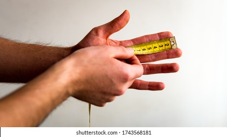 Person Measuring The Index Finger Of His Left Hand With A Yellow Tape Measure. White Background. Olive Skin Tone. 