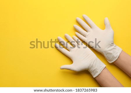Person in medical gloves on yellow background, top view. Space for text