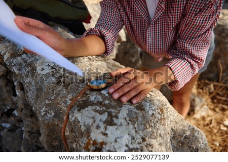 A person navigating with a compass and map on a rocky surface, embodying exploration and adventure. The scene evokes a sense of direction and outdoor discovery in daylight.