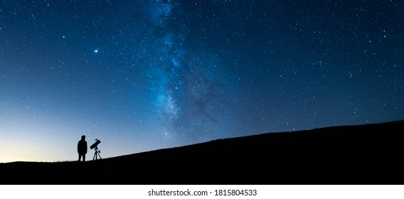 Person Observing The Blue Starry Sky With A Telescope At Night. Silhouette Of An Astronomer Observing The Immensity Of The Universe And The Milky Way