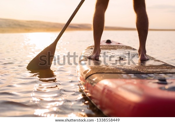 Person on paddle board at\
sunset