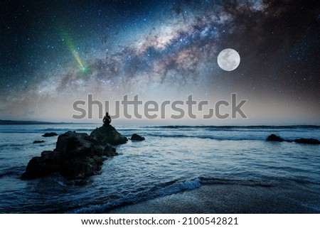 person on the rock outdoors meditating or praying at night under the Milky Way and Moon	