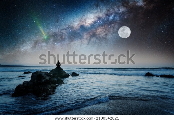 person on the rock outdoors meditating or\
praying at night under the Milky Way and\
Moon	