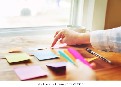 Person organizing things with pastel sticky notes at a desk