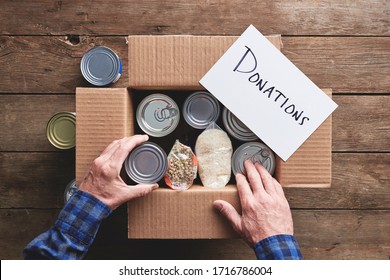 A Person Packing A Donation Box With Food Items