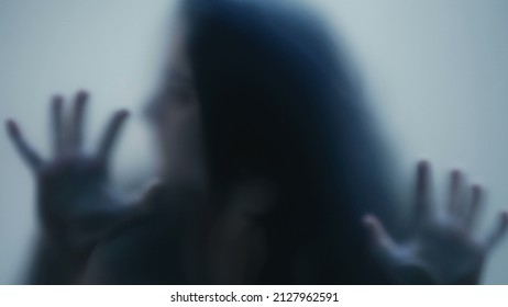 Person in pain behind glass woman suffering from depression concept feeling trapped defocused shot