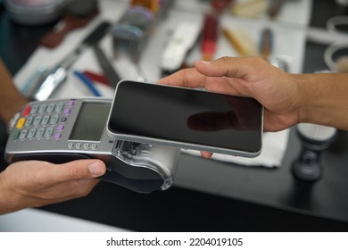 Person paying for the service using a phone and terminal - Powered by Shutterstock