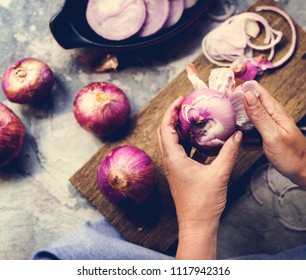 A person peeling red onion