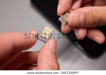 A person is performing the action of inserting a sim card into a cell phone by using hand gestures with their fingers and thumb