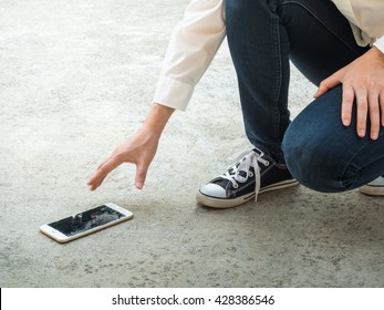 Person Picking Broken Smart Phone (Cracked Screen) of the Ground