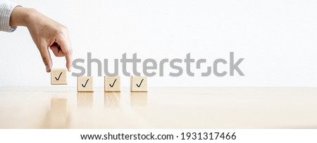 The person is picking up four rectangular wooden blocks with icons placed on them. Concept of Checklist. Banner background with copy space.