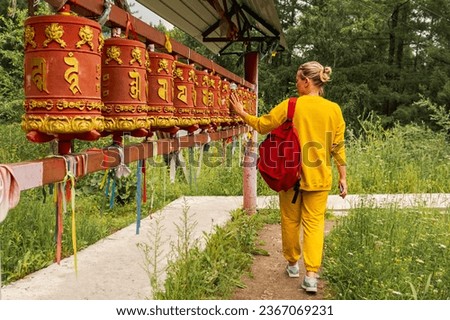 Person pilgrim woman touching turning spinning Buddhist prayer wheel at Buddhist monastery. Prayer wheels in Buddhist stupa temple. Buddhism religion concept