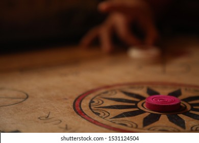 A Person Playing Carrom And Hitting Queen.