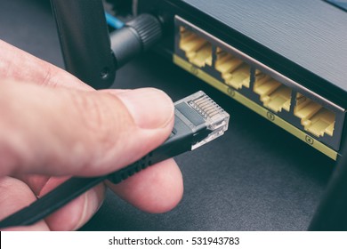 Person Plugging In Cable To Wireless Router. Close Up.