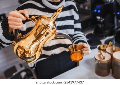 A person pouring tea from a traditional golden Arabic coffee pot into an amber glass cup. Capturing the warmth and elegance of Arabic hospitality, ideal for cultural and beverage-related themes. - Powered by Shutterstock