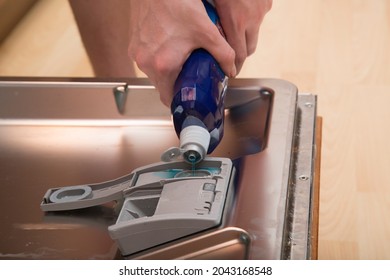 A Person Pours A Rinse Aid Into The Dishwasher.