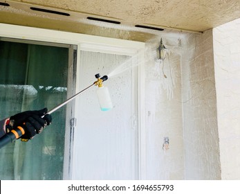 A Person Power Washing A House With A High Pressure Soap Dispenser