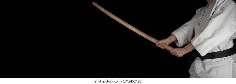 A person practicing aikido martial art on a black background.