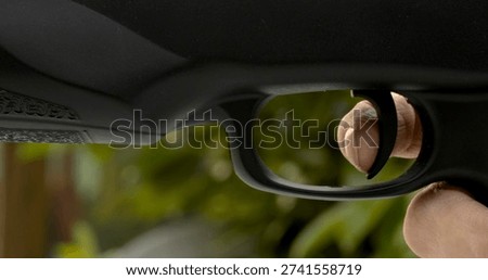 Person prepares to pull trigger on firearm in an outdoor setting during daylight hours