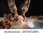 A person is preparing baking ingredients such as flour, eggs, and using various kitchen tools on a table