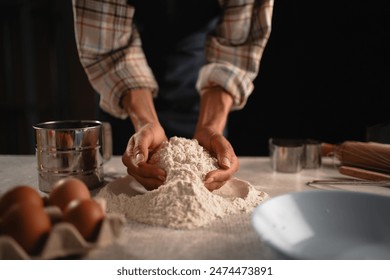 A person is preparing baking ingredients such as flour, eggs, and using various kitchen tools on a table - Powered by Shutterstock