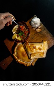 person preparing to eat a traditional chilean empanada, table top view