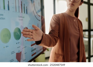 Person presenting data on an interactive screen displaying various growth metrics and charts in modern office environment