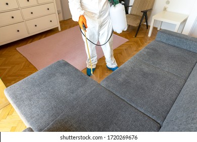 Person in protective suit with decontamination sprayer bottle disinfecting household and furniture. Coronavirus or COVID-19 pandemic disinfection concept. - Shutterstock ID 1720269676