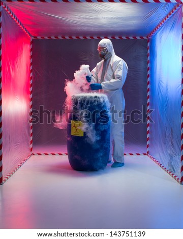 person in a protective suit and gas mask working with steaming substances over a blue waste drum marked as bio hazardous inside a containment tent