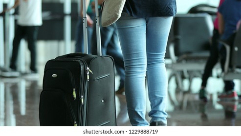 Person pulls suitcase at the airport. Woman carrying luggage