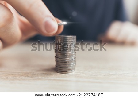 The person puts the coins into a stack of money. The concept of capitalization and investment.