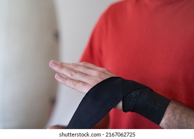 Person Putting Boxing Wrap Bandage By Boxing Bag Before Training