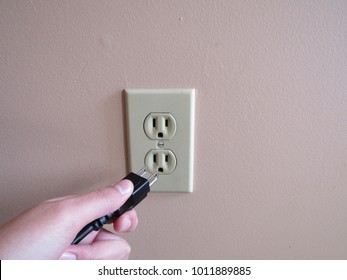 Person Putting Plug Into American Wall Outlet 