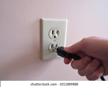 Person Putting Plug Into American Wall Outlet 