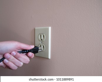 Person Putting Plug Into American Wall Outlet 