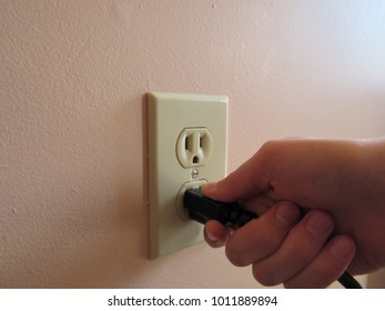 Person Putting Plug Into American Wall Outlet 