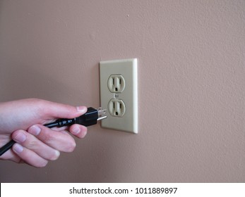 Person Putting Plug Into American Wall Outlet 