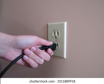 Person Putting Plug Into American Wall Outlet 