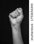 Person raised fist isolated on monochrome black background. The clenched fist, is a symbol of solidarity and support.Used as a salute to express unity, strength, defiance or resistance concept