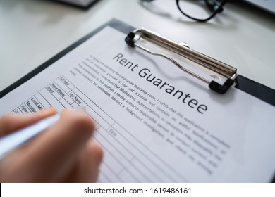 Person Reading Rent Guarantee Form Over Desk